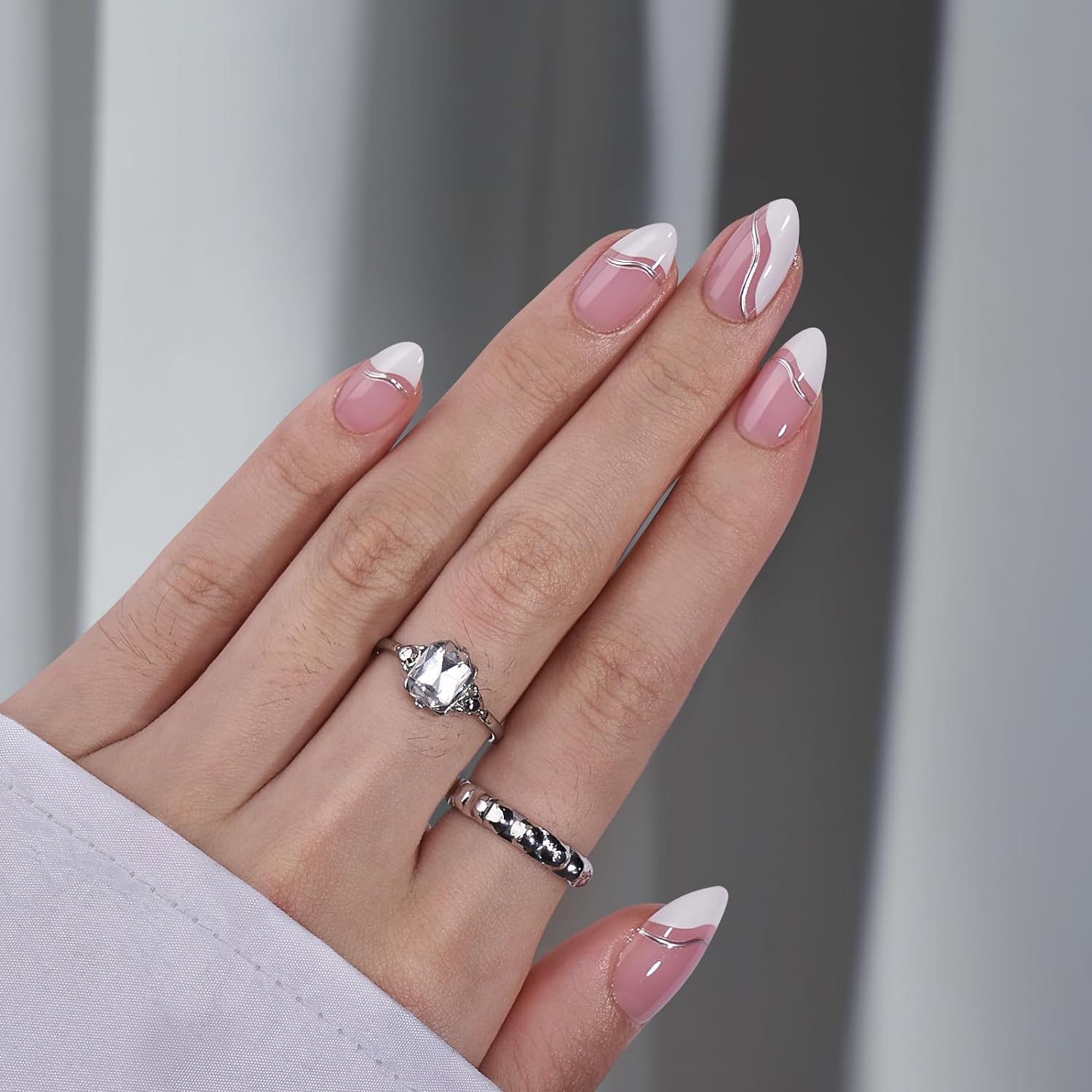 Franska press-on naglar med silver swirl – mandelform och nude bas på hand med kristallring
