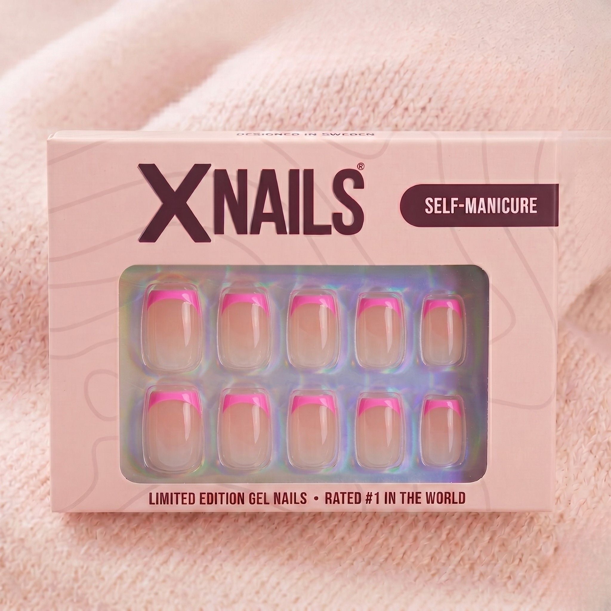 XNails-förpackning med rosa franska korta square press-on naglar mot rosa stickad bakgrund
