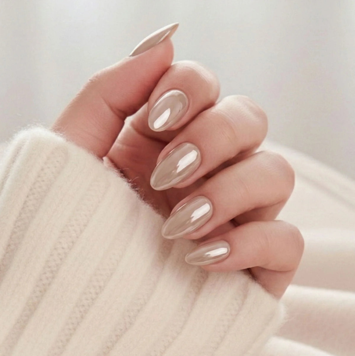Pearly Perfection press-on naglar – mandelform i pearl taupe med metallic glans mot krämvit stickad tröja