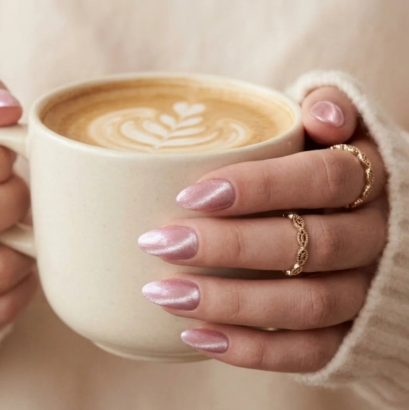 XNails press-on naglar på hand som håller en latte — rosa chrome mandelnaglar