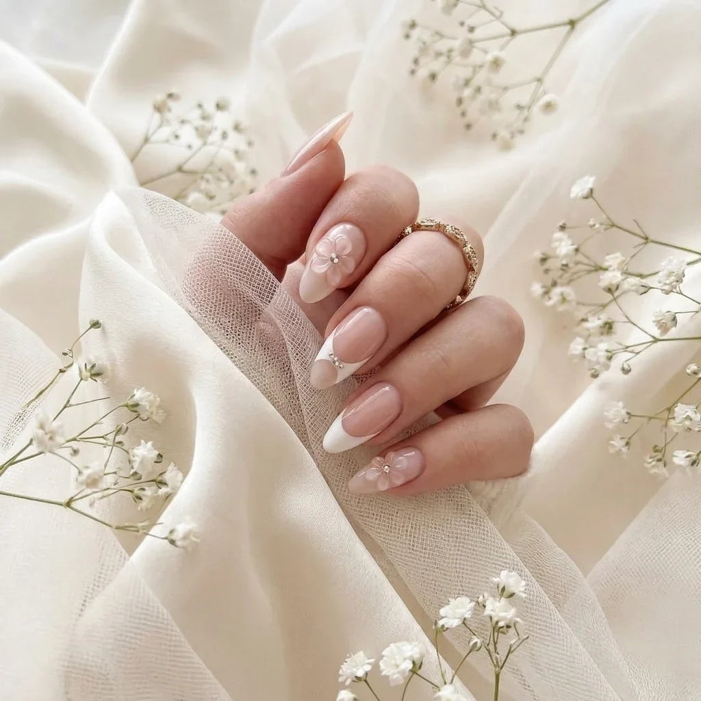 Brudens hand med Bridal Bloom press-on naglar på elfenbenssilke