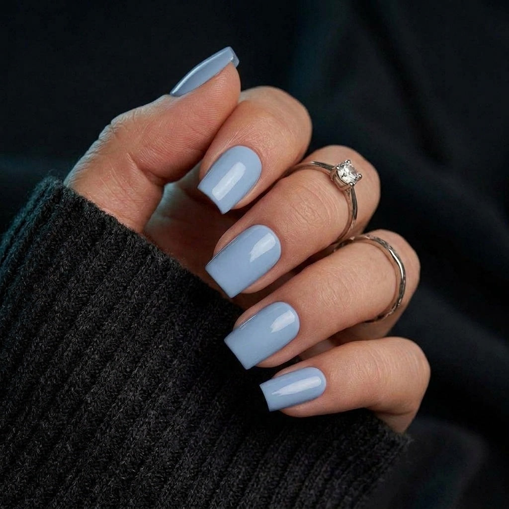 Baby Blue press-on naglar i ljusblå fyrkantig form mot mörk stickad tröja, hand med diamantring