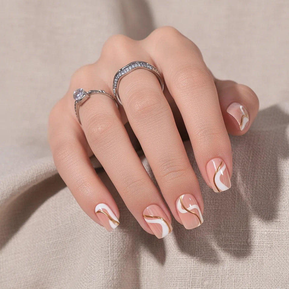 Summer Swirl square press-on naglar närbild – guld och vita swirls med silverringar mot beige linne
