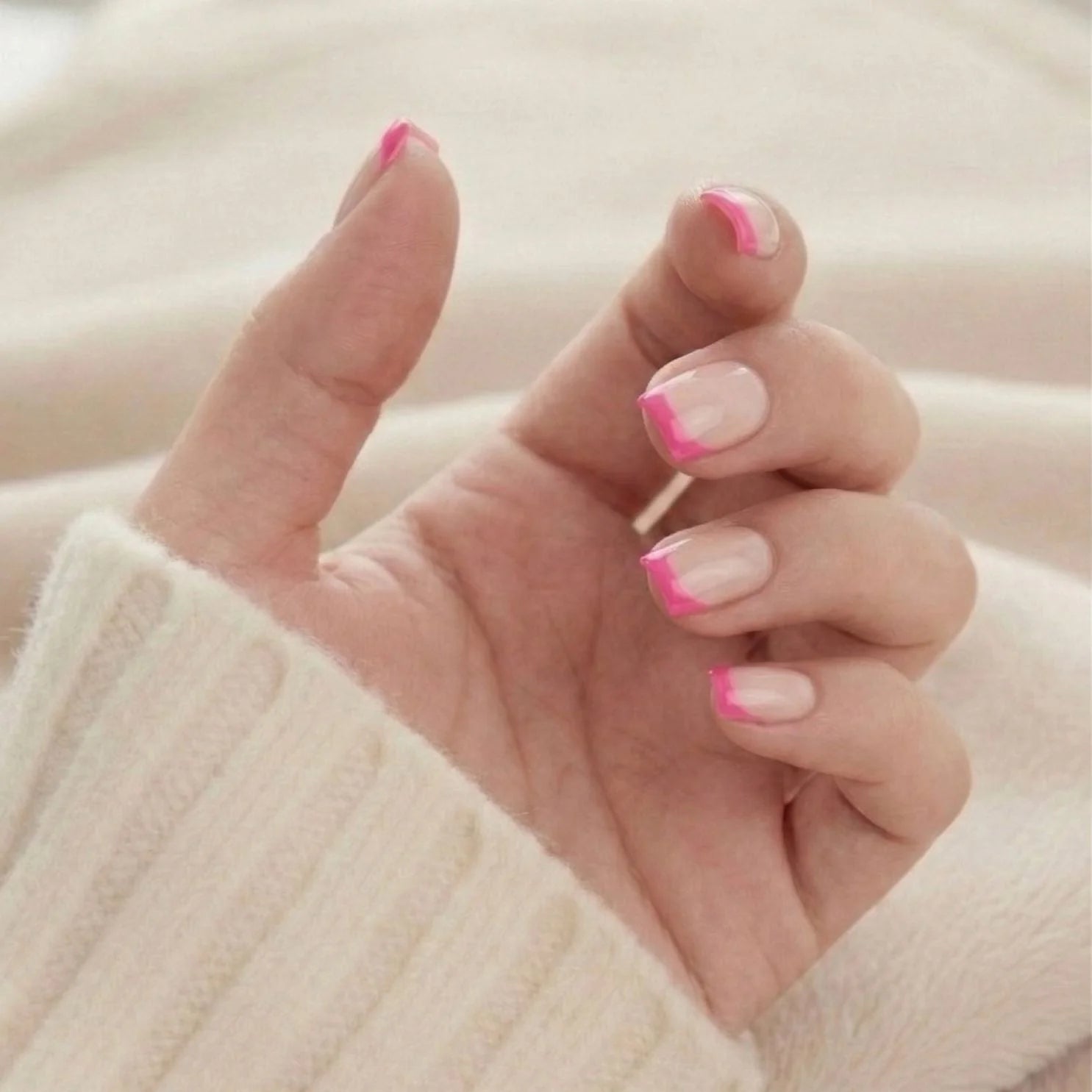 Pixie Pink korta square-lösnaglar – rosa fransk spets sedd uppåt mot stickad tröja