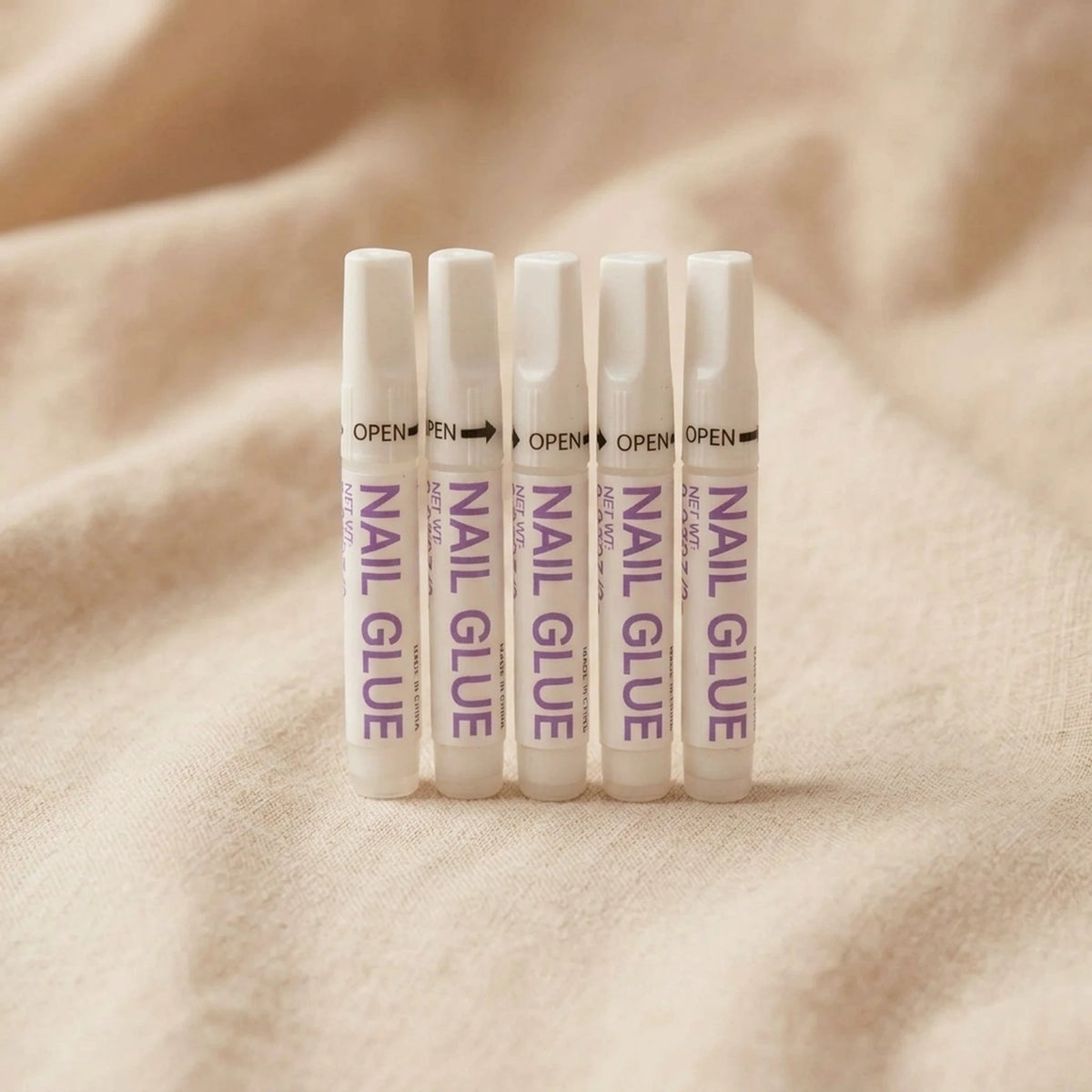 XNails Nail Glue nagellim på beige bakgrund