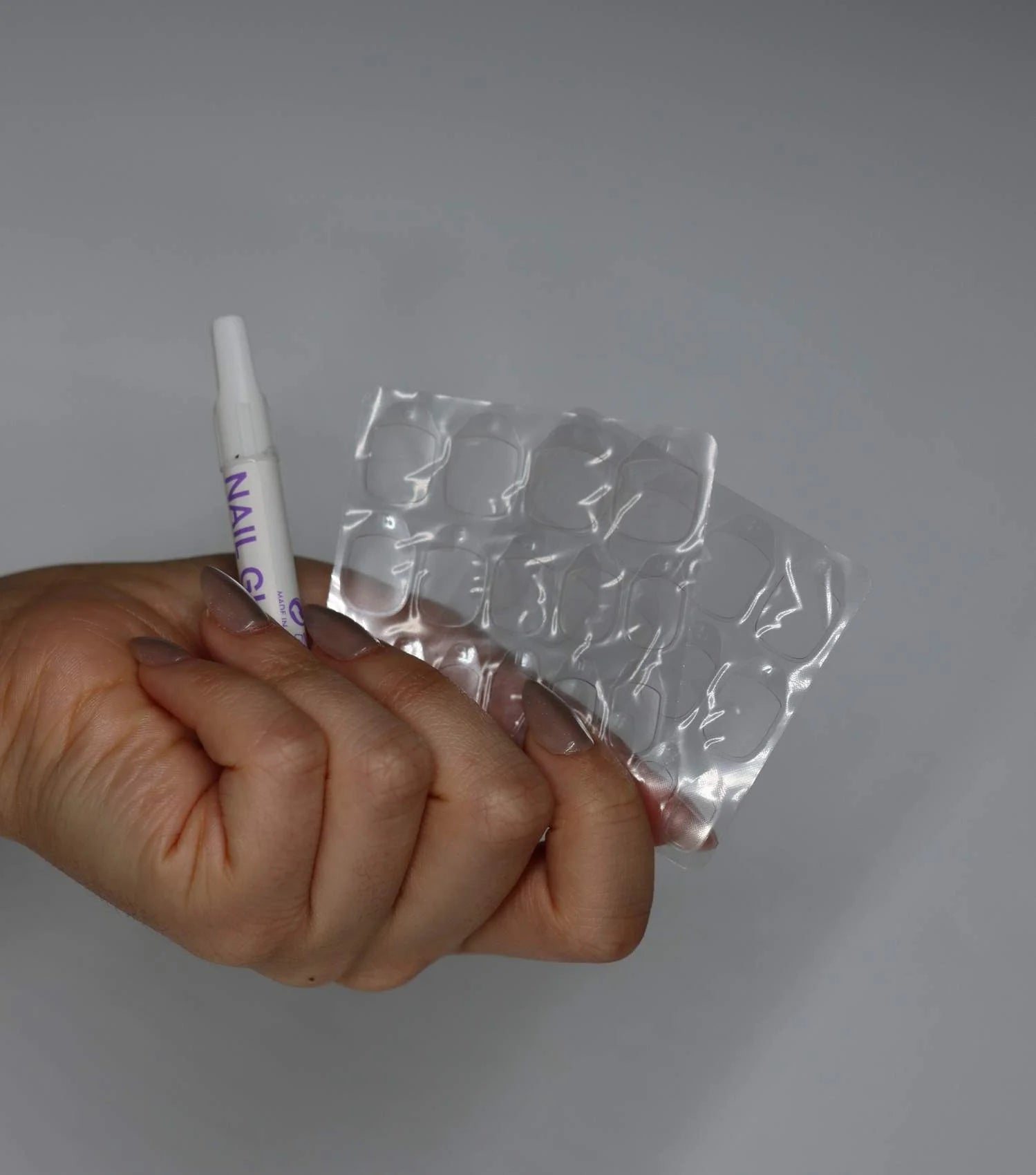 En hand håller nagellim och limtejpar